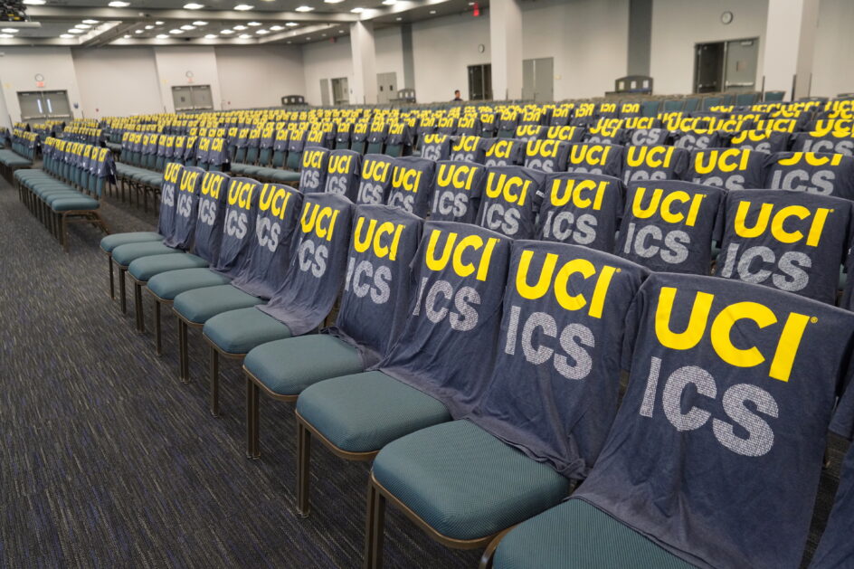 An large empty room with UCI ICS t-shirts draped over rows and rows of chairs.