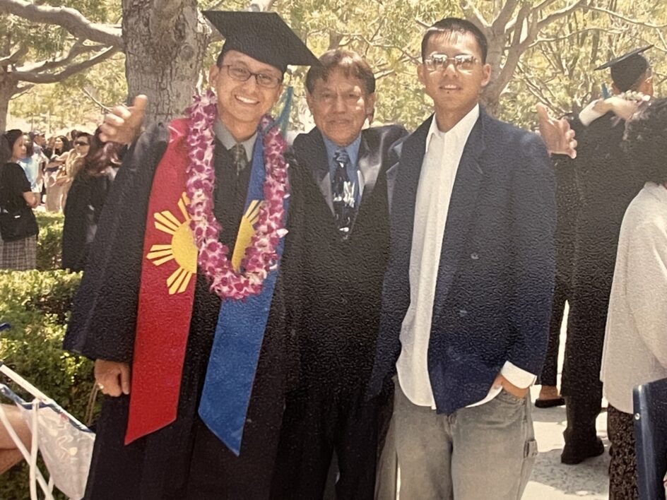 Balacy in a cap and gown standing next to his dad and brother.