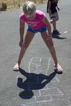 Sara plays hopscotch on the board she drew
