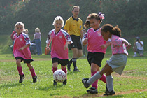 Chandler, Sara, and Kelsey watch as an Angel kicks the ball