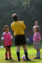 Maryam and an Angel watch as referee José flips a coin to start the game