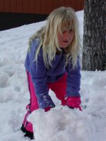 Sara rolling a snowball for another snowman